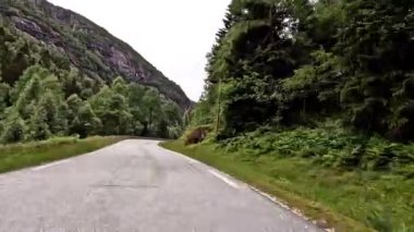 First person view of a nordic two-lane road, forest, mountains