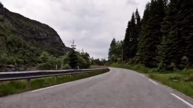 First person view of a nordic two-lane road, forest, mountains