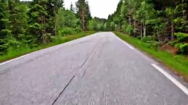 First person view of a nordic two-lane road, forest, mountains