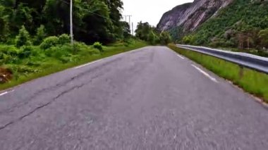 First person view of a nordic two-lane road, forest, mountains