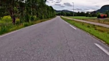 First person view of a nordic two-lane road, forest, mountains