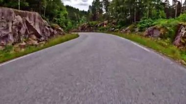 First person view of a nordic two-lane road, forest, mountains