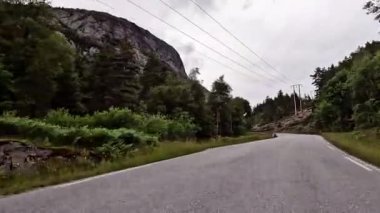 First person view of a nordic two-lane road, forest, mountains