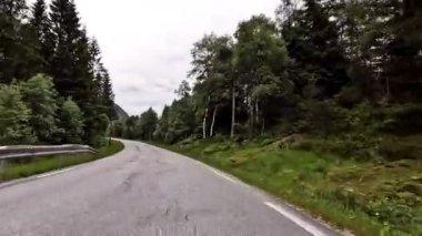 First person view of a nordic two-lane road, forest, mountains