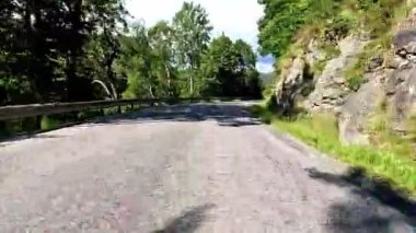 First person view of a nordic two-lane road, forest, mountains