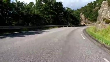First person view of a nordic two-lane road, forest, mountains