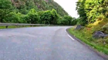 First person view of a nordic two-lane road, forest, mountains