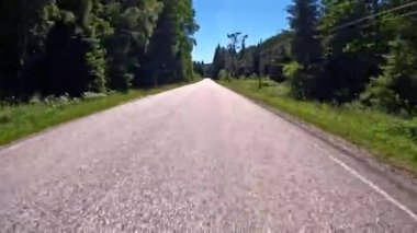 First person view of a nordic two-lane road, forest, mountains