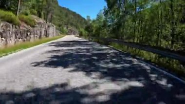 First person view of a nordic two-lane road, forest, mountains