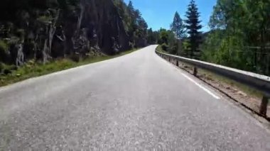 First person view of a nordic two-lane road, forest, mountains
