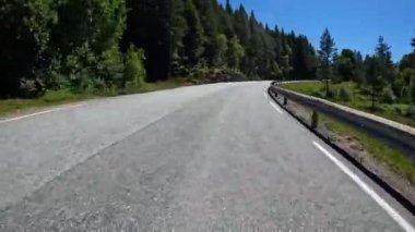 First person view of a nordic two-lane road, forest, mountains