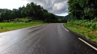 First person view of a nordic two-lane road, forest, mountains
