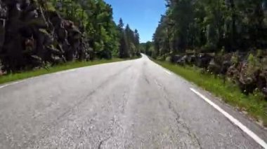First person view of a nordic two-lane road, forest, mountains