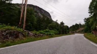 First person view of a nordic two-lane road, forest, mountains