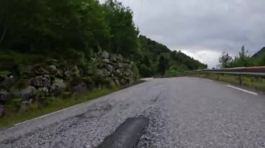 First person view of a nordic two-lane road, forest, mountains