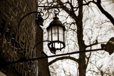 Duvarda asılı bir sokak lambası var. siyah beyaz fotoğraf. Duvardaki fener.