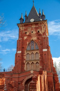 Gotik tarzında yüksek bir bina. Eski bir bina. Mimarinin tarihi anıtı. Bina mavi gökyüzüne karşı kırmızıdır..