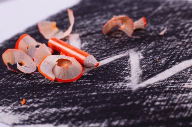 Siyah arka planda bir kalem. turuncu kalem. Siyah arkaplanda bir yazı var. Kalem talaşı. kalem atığı