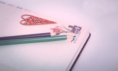 Not defterinde renkli kalemler var. Beyaz bir arka planda not defteri. kırmızı kalp.