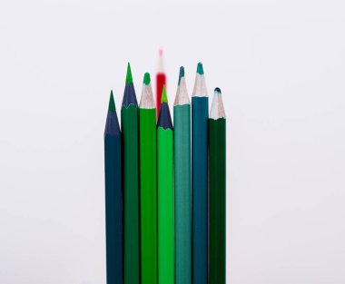 Önde bir grup kalem, arkada da bir kalem var. Önde bir kalabalık, arkada bir yalnız. Yeşil kalemler yakın plan, kırmızı kalem arkada. Kalemler insanlar gibidir. Kalemler kalabalığı betimler.