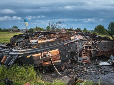 Ukrayna 'da savaş, sökülmüş bir taret tankın yanında yatıyor, bir sivil bir tankın kalıntılarını inceliyor, kırsal kesimin arka planına karşı enkaz bir tank.