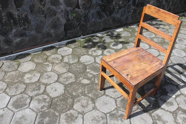 Simple Wooden Chair. Indonesian Javanese traditional wooden chairs, on the paving floor of the front yard, in the morning, with negative space for text.