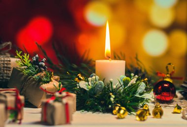 Noel arkaplanı. Ahşap bir masada yanan mum ve Noel hediyeleri.