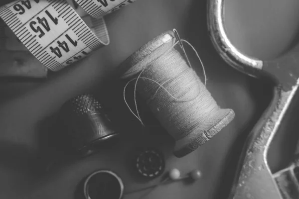 Retro tools for the work of a tailor, seamstress, fashion designer. Needle with thread, scissors, thimble, buttons and centimeter.