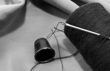 Siyah-beyaz kumaş arka planında eski model iplik makarası. İplikle iğne yap