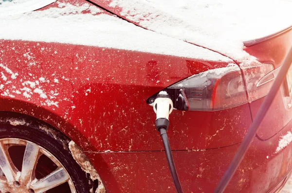 Bir elektrikli araba kışın bir elektrik şarj istasyonundan şarj edilir. Çevre taşımacılığı. Piller üzerinde taşıma