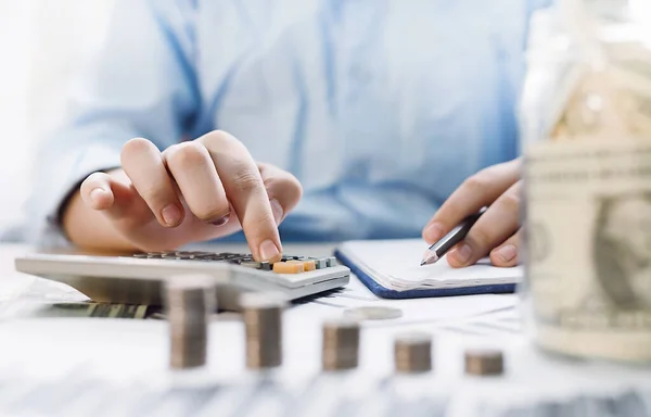 Bir iş adamı ya da finansal analist hesap makinesine para sayar ve karını bir deftere yazar. Gelir. Finans ve bankalar