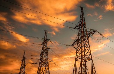 Gün batımında yüksek voltajlı elektrik hatları. Elektrik tehlikelidir.