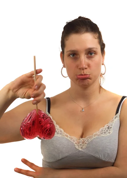 Sad young woman hold heart shaped lollipop upside down — Stock Photo, Image