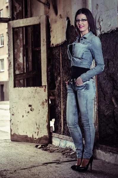 Meisje in spijkerbroek poseren in ruïnes. — Stockfoto