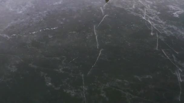 Vista aerea. Pattinaggio su ghiaccio all'aperto. Uomo in giacca gialla pattinaggio sul lago ghiacciato trasparente. — Video Stock