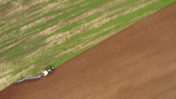Vliegen over de trekker in het veld. Tractor werkt in het veld top-down zicht. Het proces van ploegen van het veld met een trekker — Stockvideo