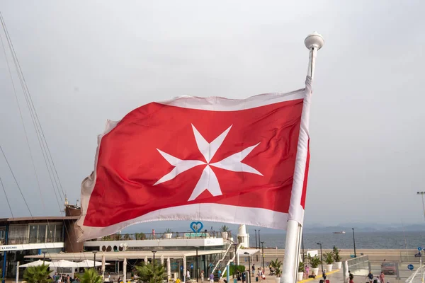 停泊在希腊码头的一艘豪华船上悬挂马耳他国旗 古老的马耳他国旗 红色背景上的白色十字在船尾摇曳 蓝天背景 — 图库照片