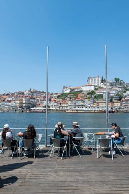 Porto, Portekiz. 26 Mayıs 2022. Porto, Portekiz 'de güneşli bir günde Douro Nehri kıyısındaki restoranda yemek yiyen insanlar.