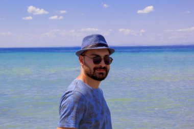 Kumsalda güneş gözlüklü yakışıklı bir adam.