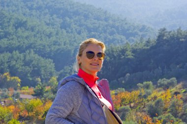 Güzel genç bir kadın kameraya gülümsüyor.