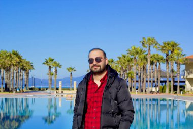 Havuzda güneş gözlüklü yakışıklı bir adam.