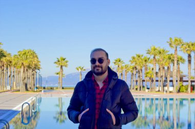 Havuzda güneş gözlüklü yakışıklı bir adam.