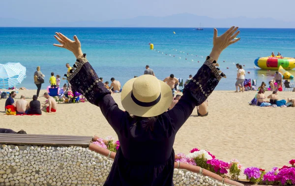 Kumsalda şapkalı ve siyah elbiseli güzel bir kadın.