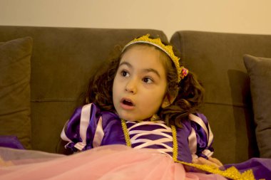 Prenses elbisesi giymiş, şaşkın bakışlı hoş bir kız.