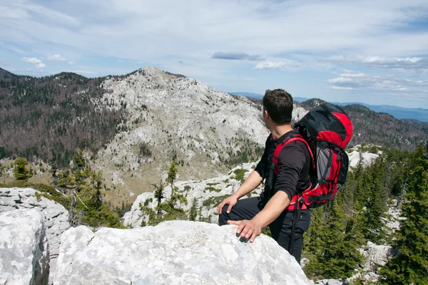 Mountaineer olha do alto da colina na outra montanha — Fotografia de Stock