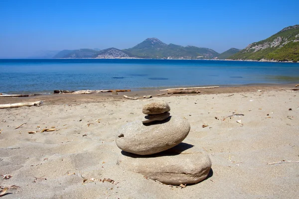 Hromadu kulaté kameny naskládané v písku na pláži — Stock fotografie