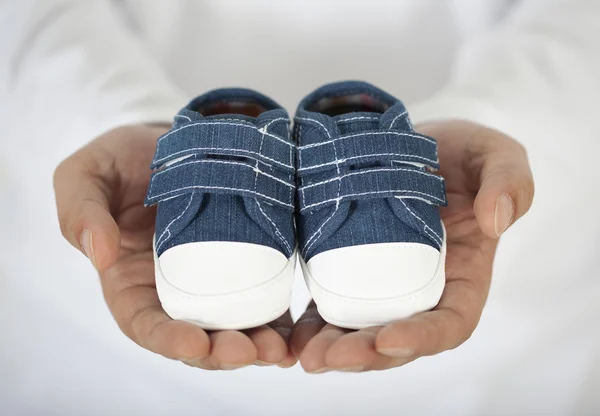 Hombre sosteniendo zapatos de bebé en blanco — Foto de Stock