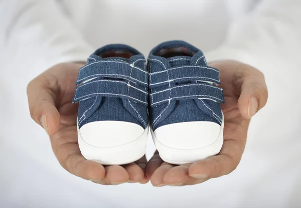 Homme tenant des chaussures de bébé en blanc — Photo