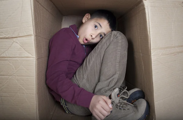 Martwi się nastoletni chłopak siedzi w tekturowym pudełku — Zdjęcie stockowe