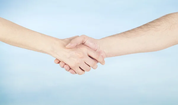 Hand skaka mellan en man och en kvinna på himmel bakgrund — Stockfoto